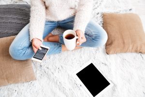 woman sitting on carpet with coffee, phone and and a tablet 